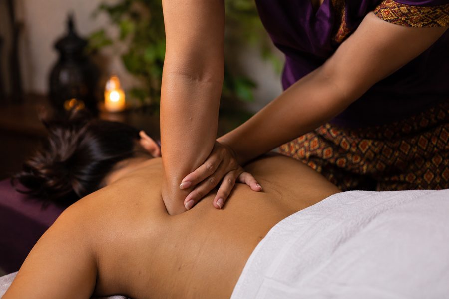 Deep tissue massage: therapist applying elbow pressure to a client's shoulder